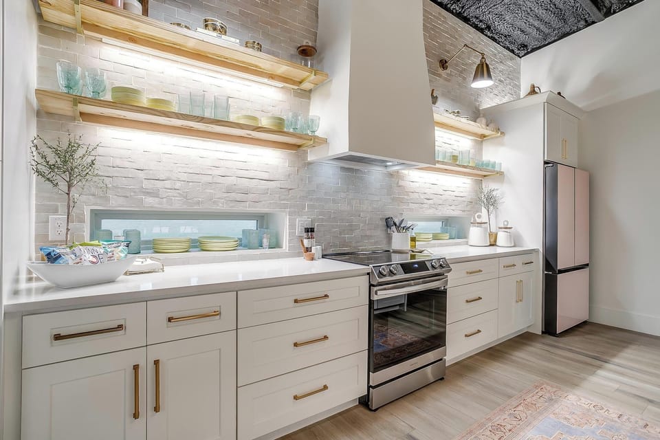 White brick, gold hardware, open shelving, and a pink refrigerator that earns every compliment it gets. The kitchen at The Noir is fully equipped and designed well enough to be the reason you book, not just a feature you use.