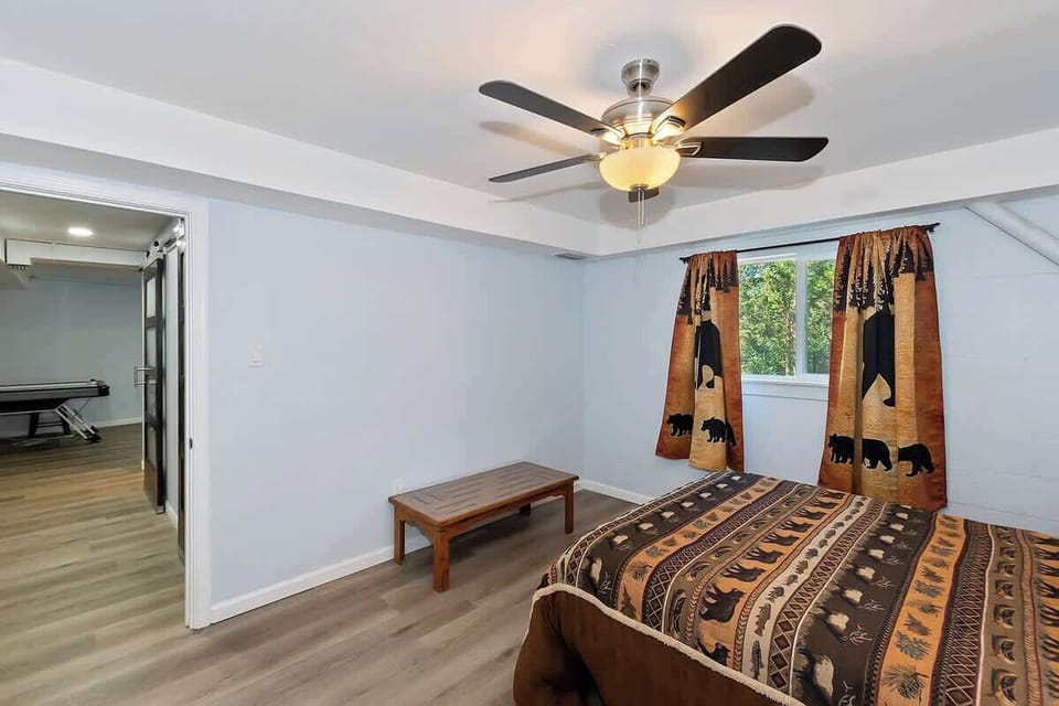 Downstairs bedroom with queen bed, ceiling fan with light