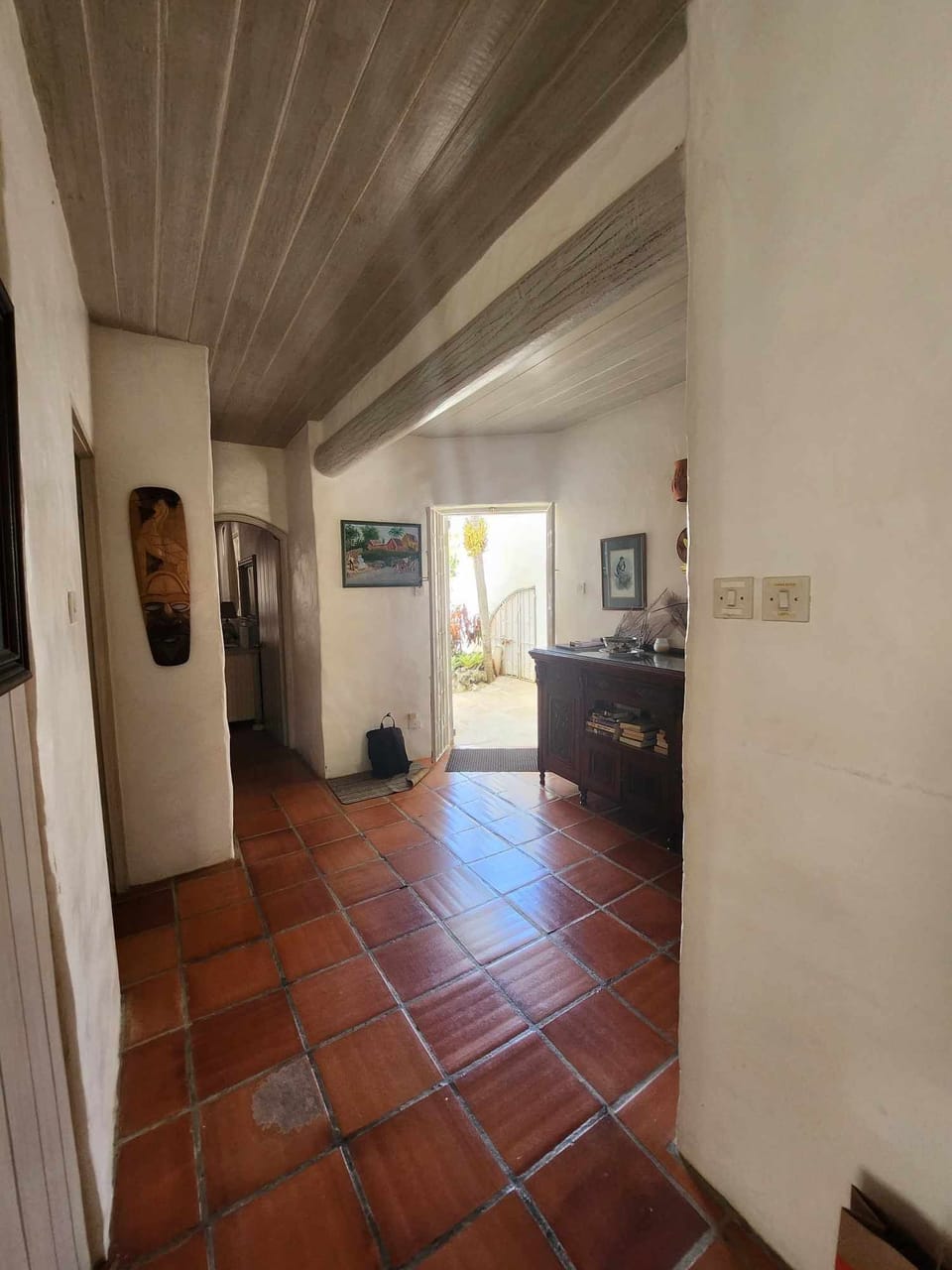 Hallway. Red floor tiles and wooden ceilings throughout.