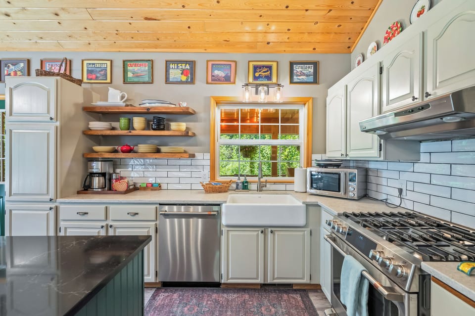 Updated kitchen with gas range, farmhouse sink, quartz island, stainless appliances and a large island.