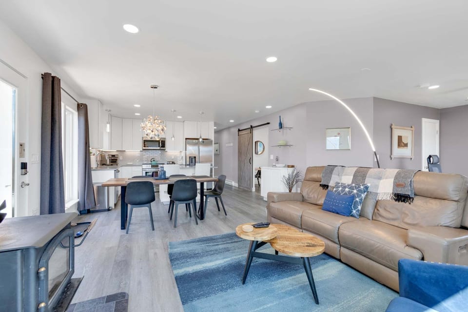 Open concept living and dining room with a wood burning stove and streaming TV