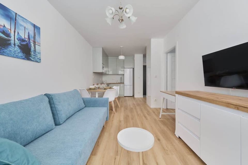 A spacious living room with a blue sofa, TV, and a modern coffee table, perfect for unwinding.
