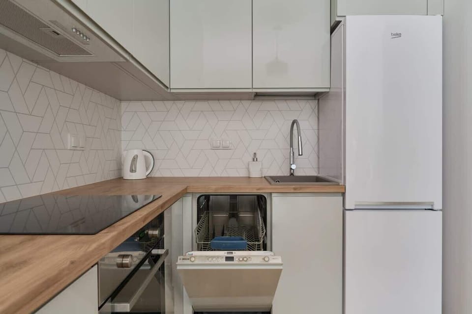 A modern kitchen with wooden countertops, a tiled backsplash, and a built-in refrigerator for convenience.
