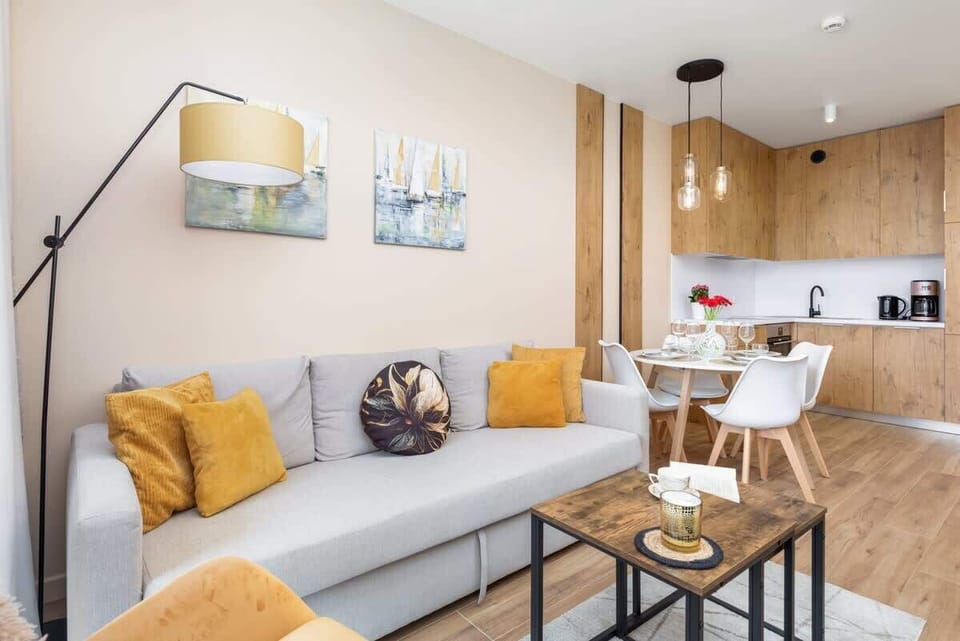 A living room with a sofa, bright cushions, and an open-plan layout connecting to the kitchen.
