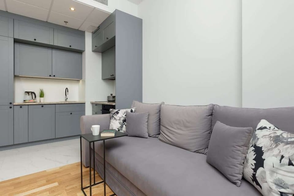 A closer look at the living room, featuring a gray sofa with patterned pillows and a small, round coffee table for convenience.

