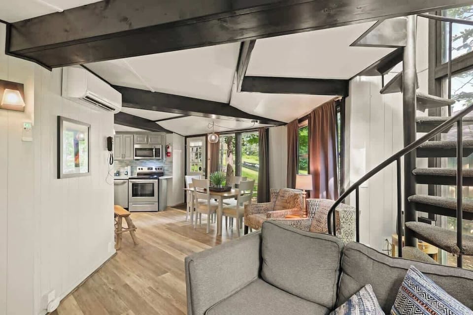 Inviting living room with a stylish spiral staircase, seamlessly extending to the well-appointed dining space and kitchen. A blend of comfort and functionality in one captivating space.