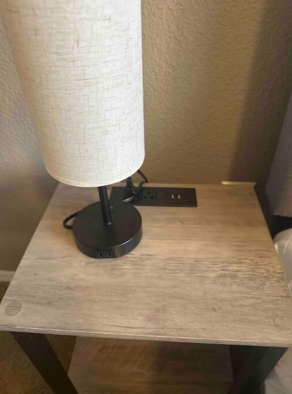Nightstands with lamps and outlets to the left and the right of Queen bed.