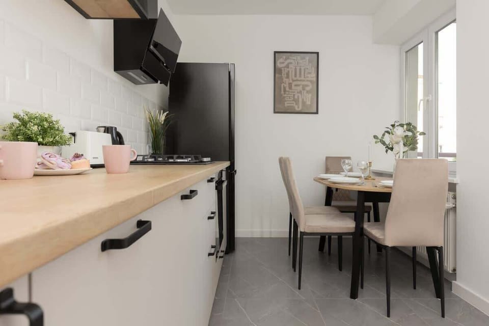 A dining area with a wooden table, modern chairs, and a bright window, seamlessly connected to the kitchen for a functional layout.

