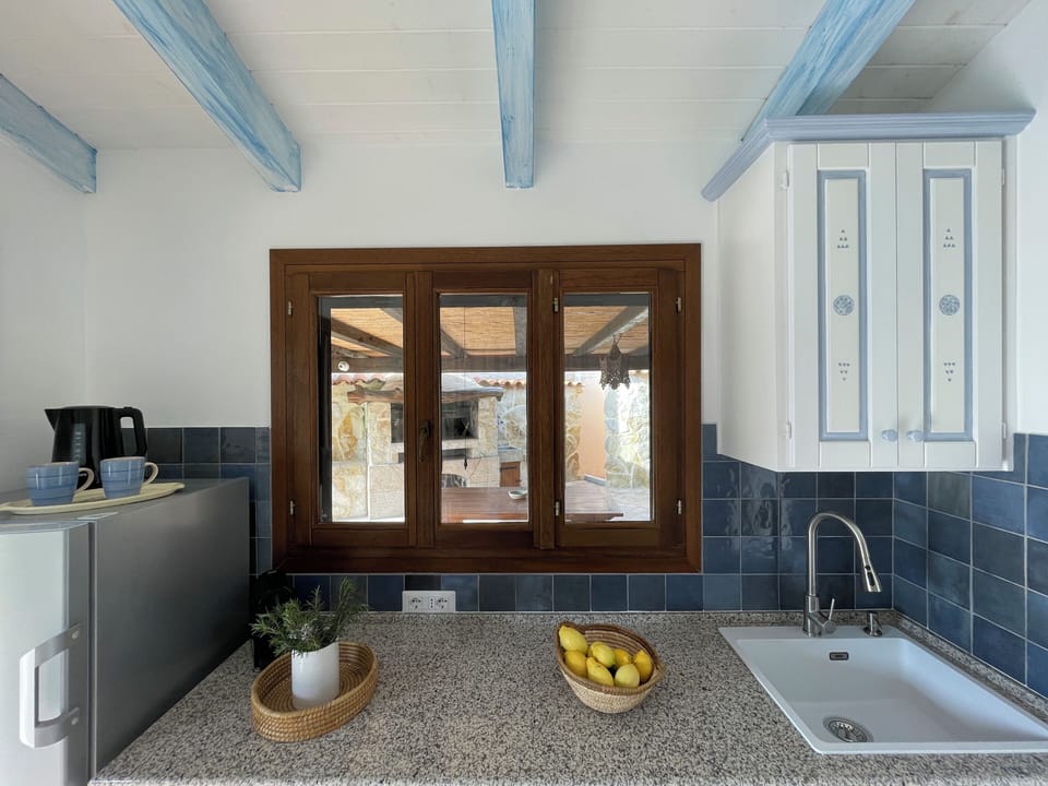 Kitchen window overlooking the external BBQ area with dining table