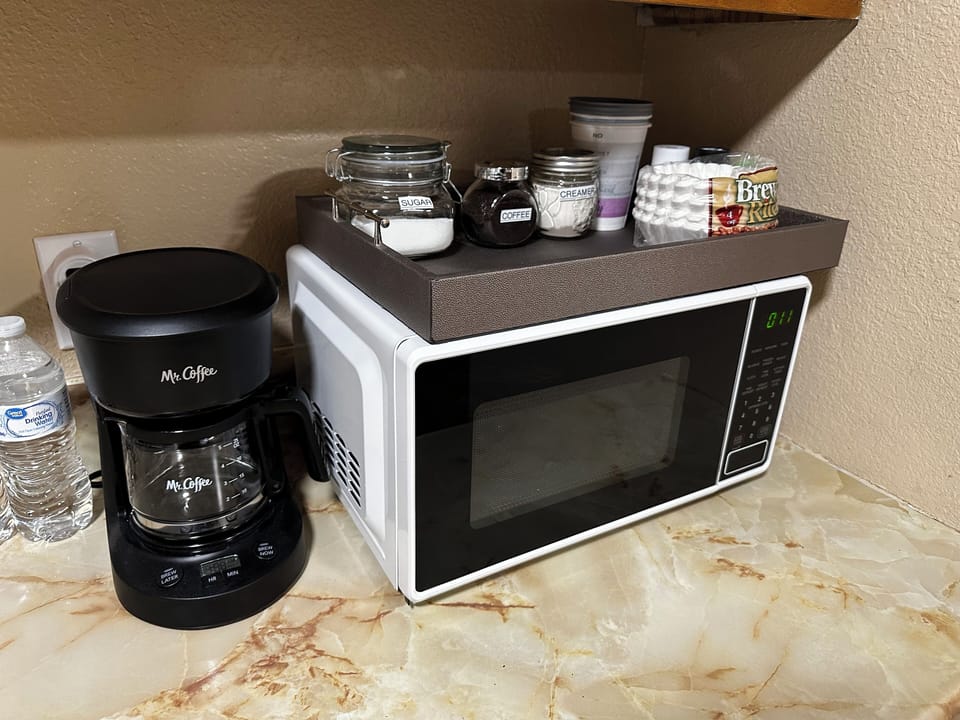 Microwave, coffee maker with coffee, sugar and creamer and coffee filters and to go cups for coffee.