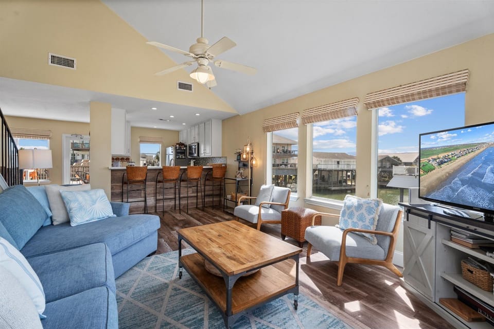 Spacious open-concept living room with cozy seating, natural light, and seamless flow to dining and kitchen.