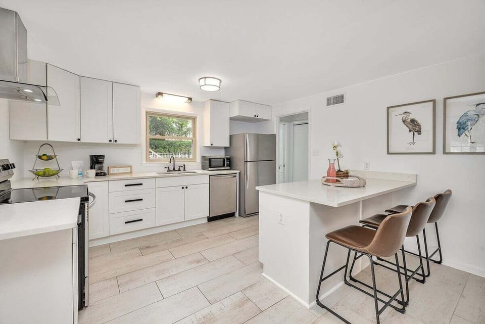 Kitchen with white island, bar stools, and stainless appliances