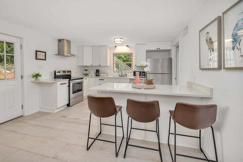 Kitchen island with bar stools and white cabinets beyond