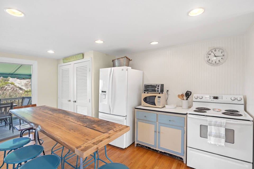 Another view of kitchen and refrigerator with filtered water/ice maker.  Stove with oven, microwave, toaster oven.  White doors lead to a pantry close