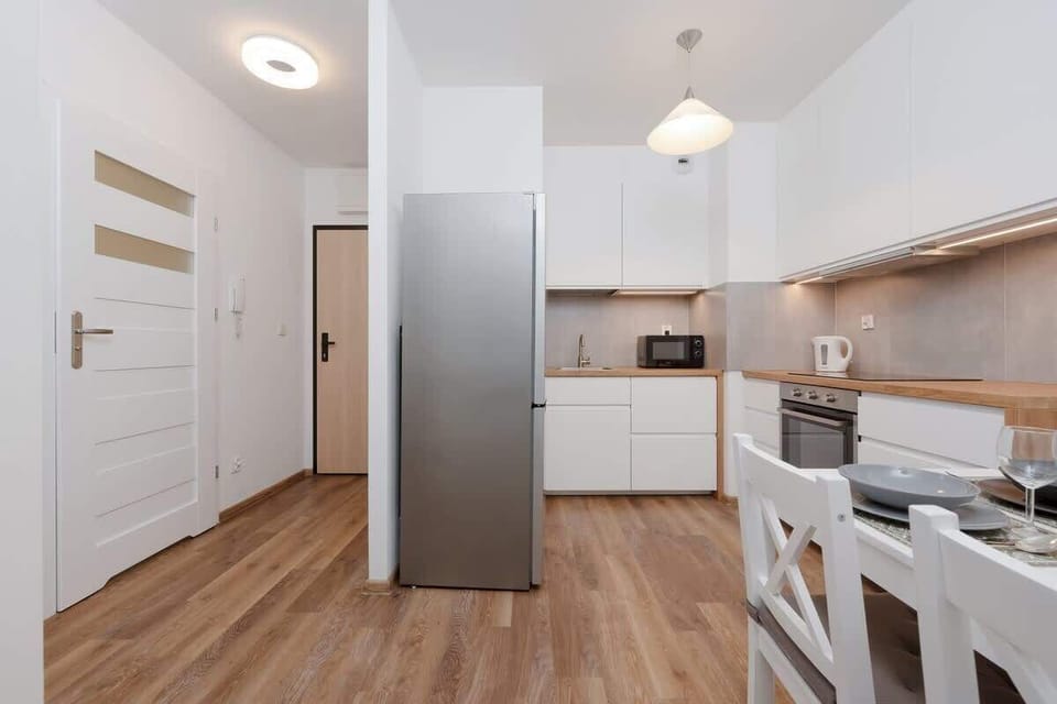 A dining and kitchen area with white furniture, light wooden floors, and an open-plan layout for a functional space.

