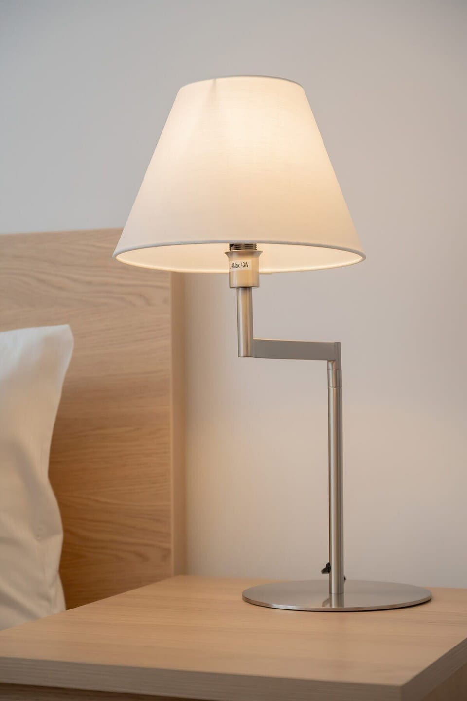 A bedside table with a simple lamp and a light wooden finish, complementing the soft tones of the bedroom.


