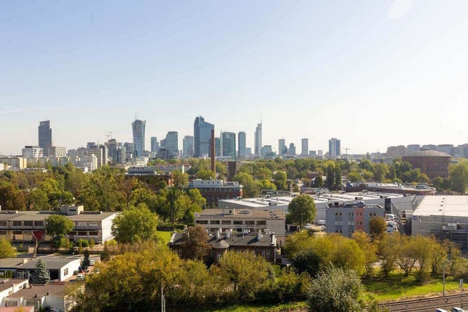 A panoramic view of the city skyline surrounded by greenery, showcasing a stunning urban landscape.

