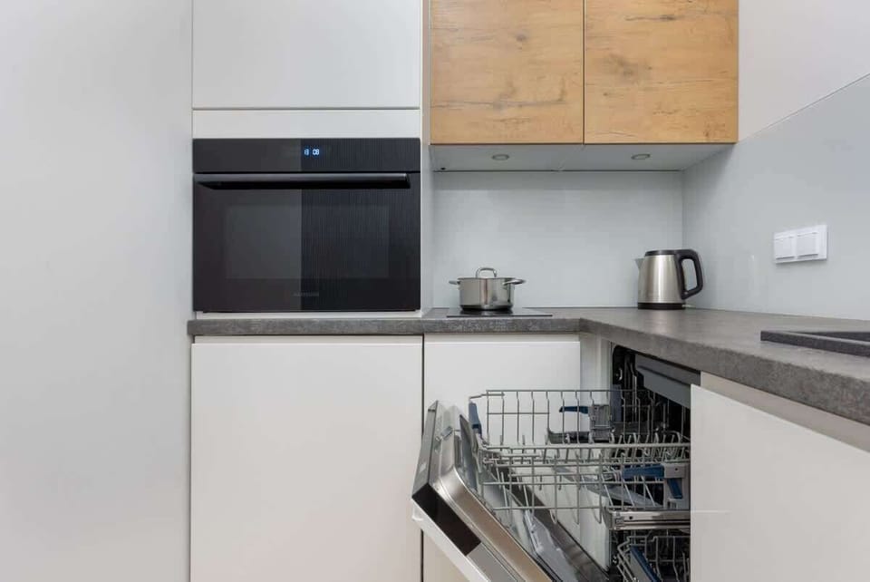 A close-up of the kitchen showing a built-in dishwasher, wooden accents, and clean, white finishes for a modern design.

