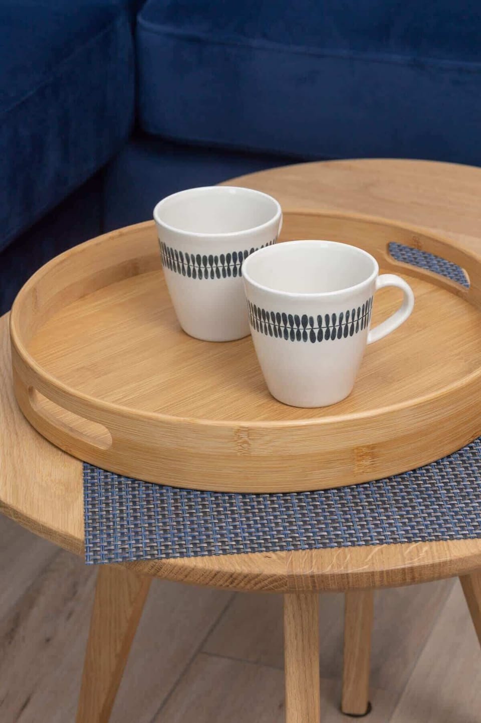 A close-up of a wooden coffee table with two mugs, adding a cozy and personal touch to the living room.

