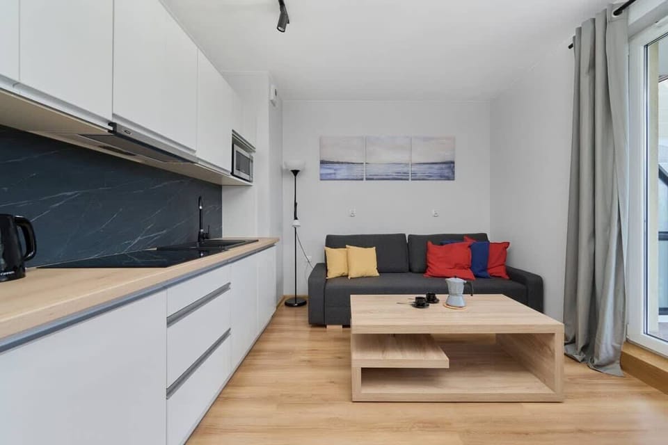 A compact kitchen with white cabinets, a sleek black backsplash, and an open view into the living area, combining modern style and practicality.

