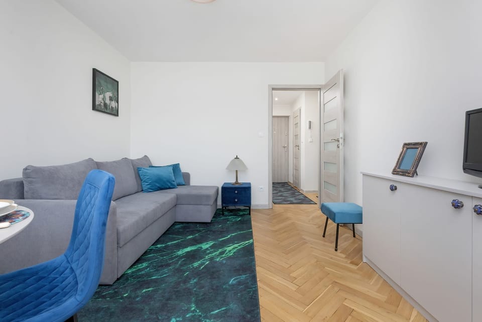 A wider perspective of the living and dining area, showing the blue furniture and bright, open layout.

