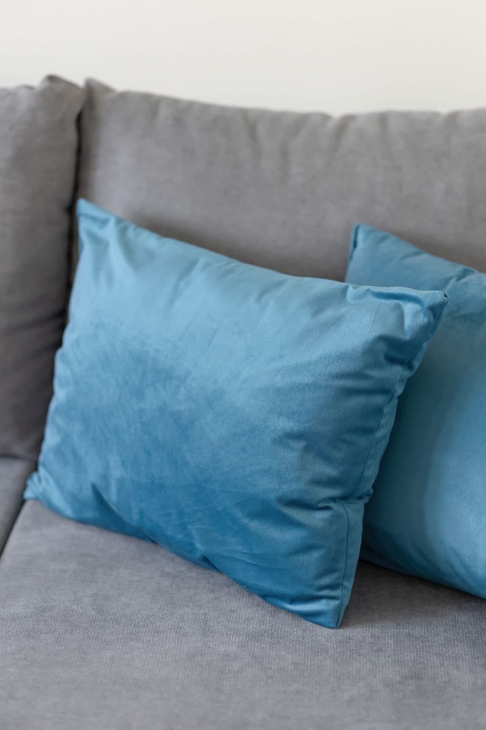 A close-up of a gray sofa with a bright blue cushion, adding a pop of color and a cozy touch to the living room.

