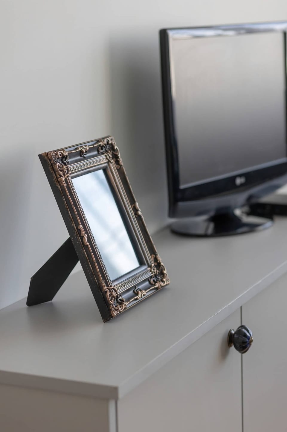 A decorative corner featuring a small TV on a white cabinet and a framed photo, adding a personal and homey touch.

