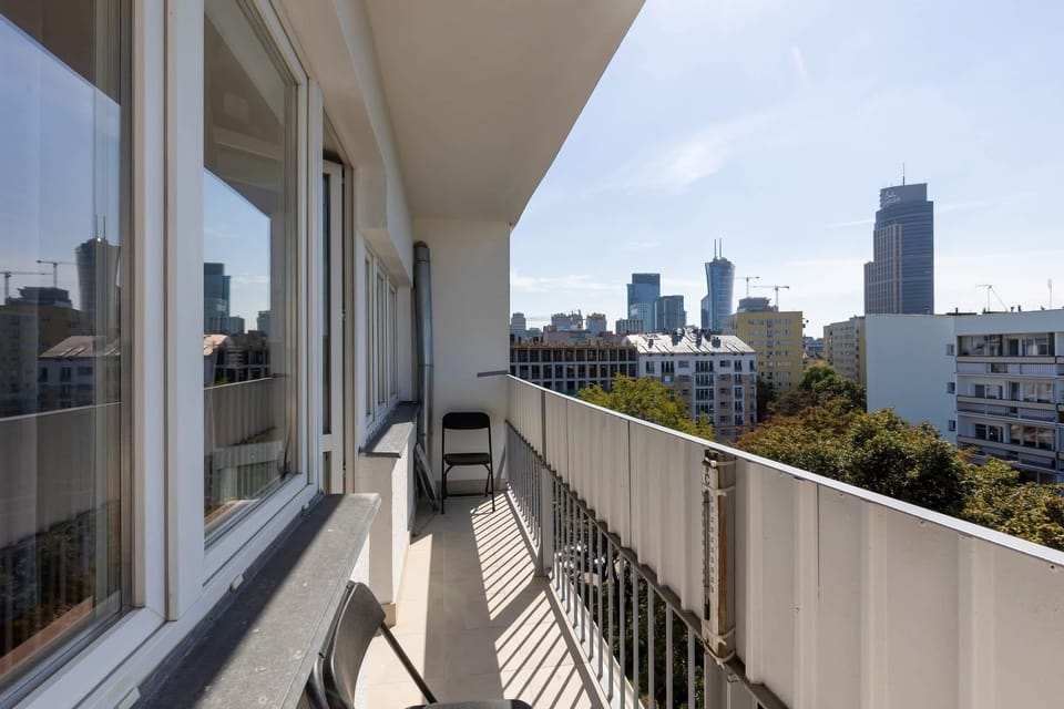 A spacious balcony with a view of the city skyline, featuring railings and ample space for relaxation.

