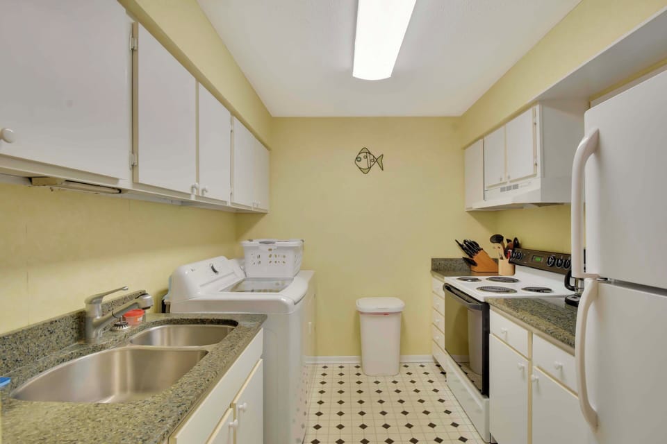 Kitchen with Granite Counters and White Cabinets - The galley-style kitchen features granite counters, white cabinets, full-size appliances, and a window to keep things bright—everything you need for island-style cooking.