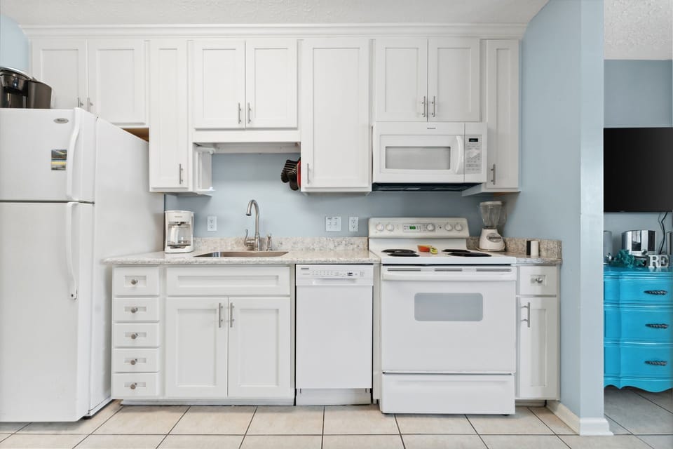Compact kitchen with white cabinetry and essential appliances for convenient cooking.