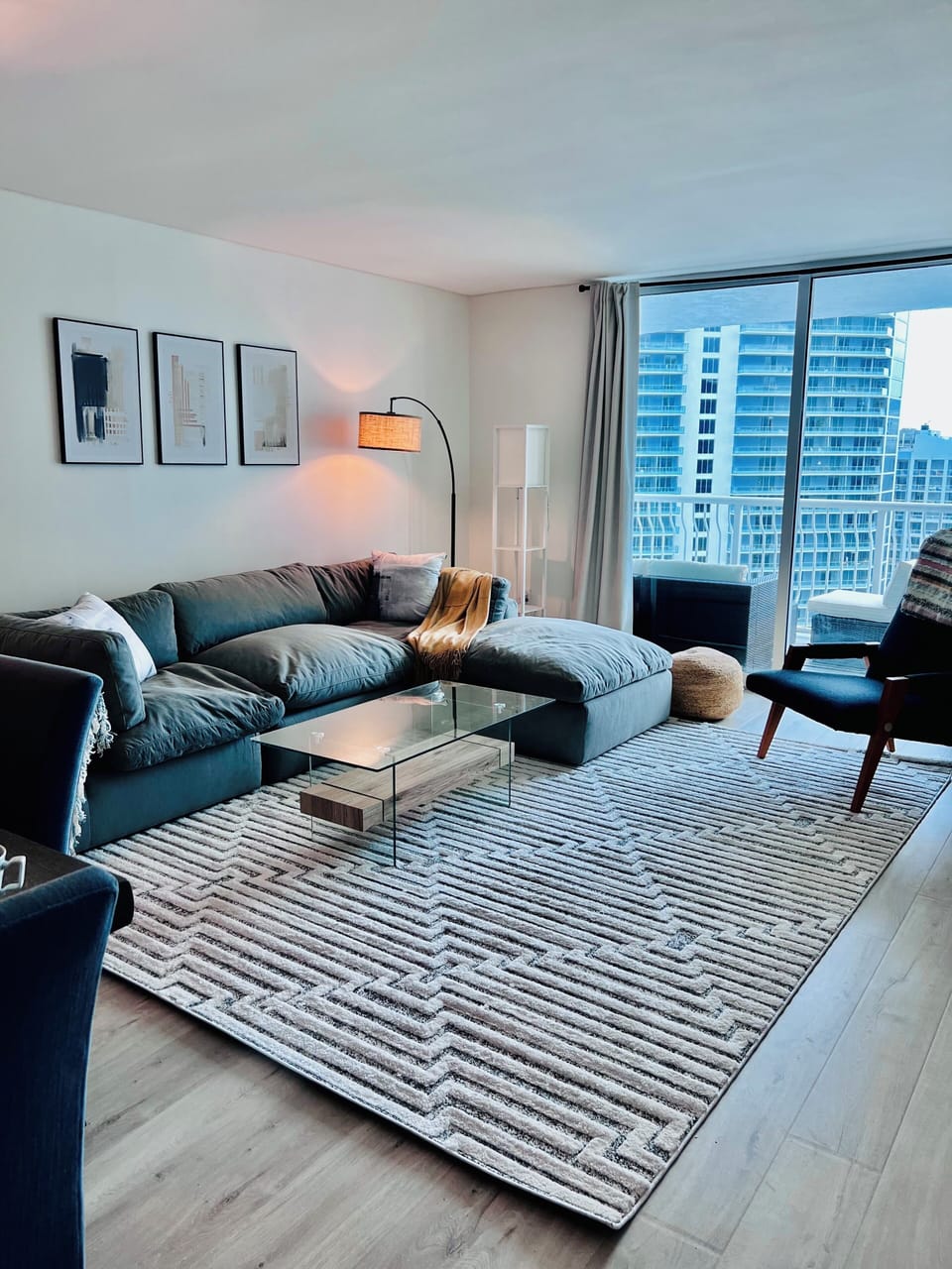 Living room opens to balcony. 65” UHD TV.