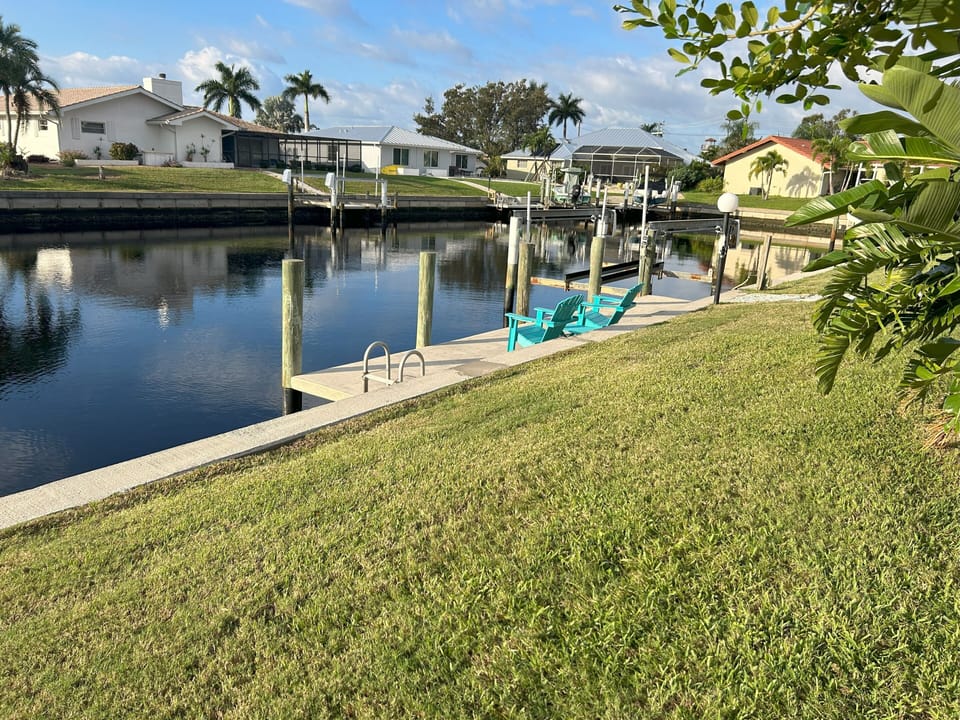 Canal, boat lift, and sun chairs