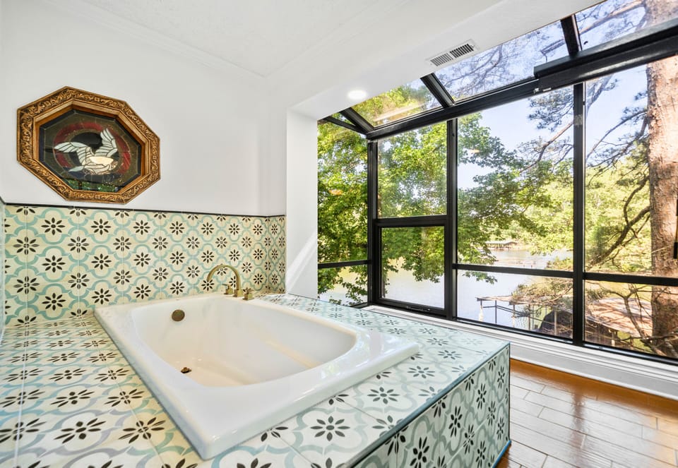 Relaxing in the tub feels even better with sunlight pouring through the surrounding windows and tree views outside.