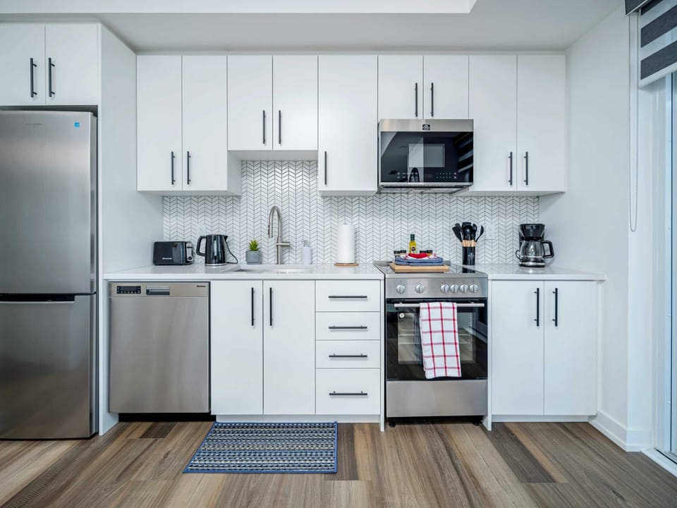 Fully Equipped Kitchen With Sleek White Cabinets And Stainless Steel Appliances
