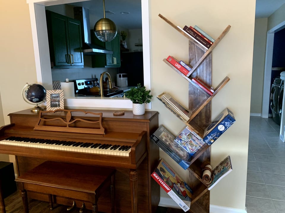 An upright piano and book tree complete with games, puzzles and sheet music.