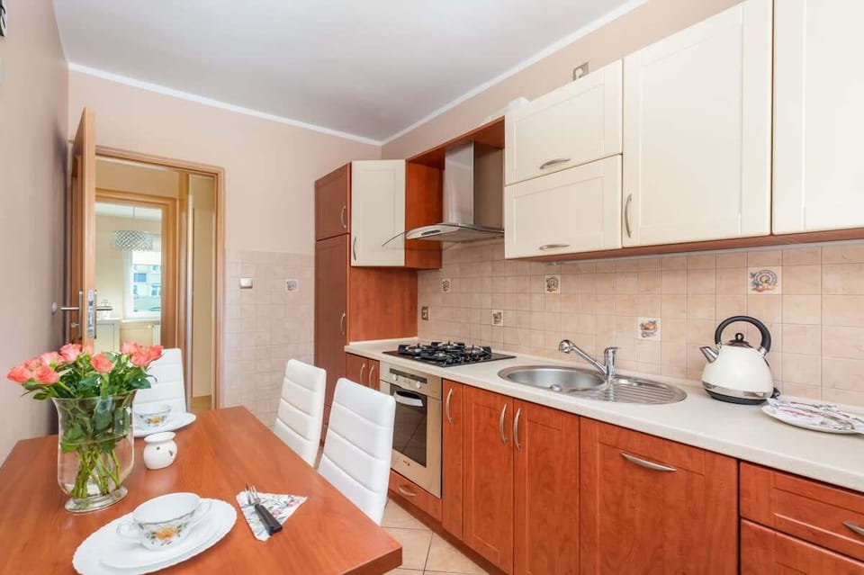 A traditional kitchen with white tiles, wooden cabinetry, and a window allowing natural light to brighten the space.

