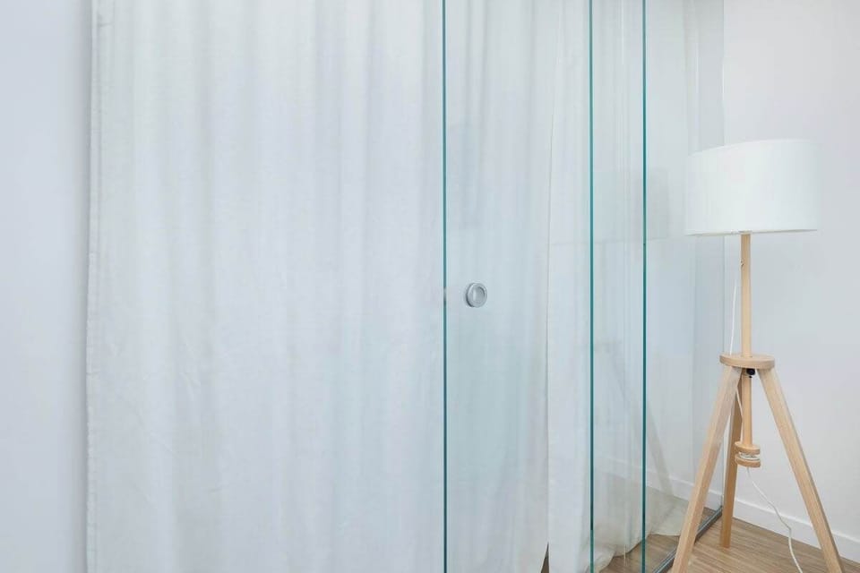 A minimalist corner with a floor lamp and sheer curtains, adding a cozy touch to the room.

