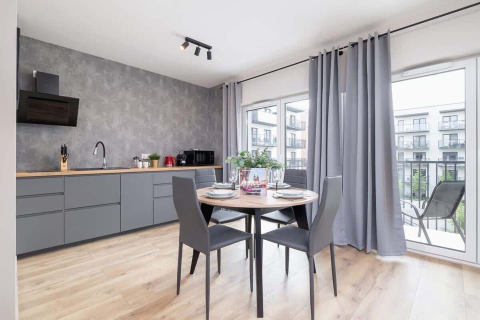 A stylish kitchen with gray cabinets, a dining area, and large windows, providing a bright and inviting space for meals.

