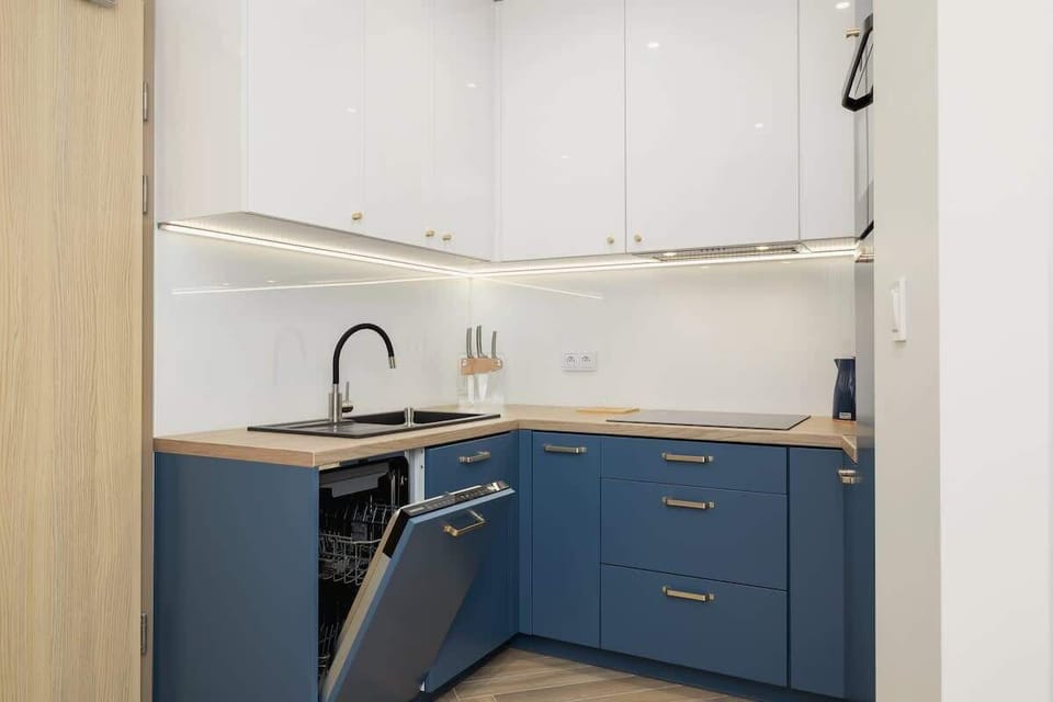 A kitchen view with white upper cabinets and blue lower cabinets, accentuated by a black sink and faucet, maintaining a clean and modern aesthetic.
