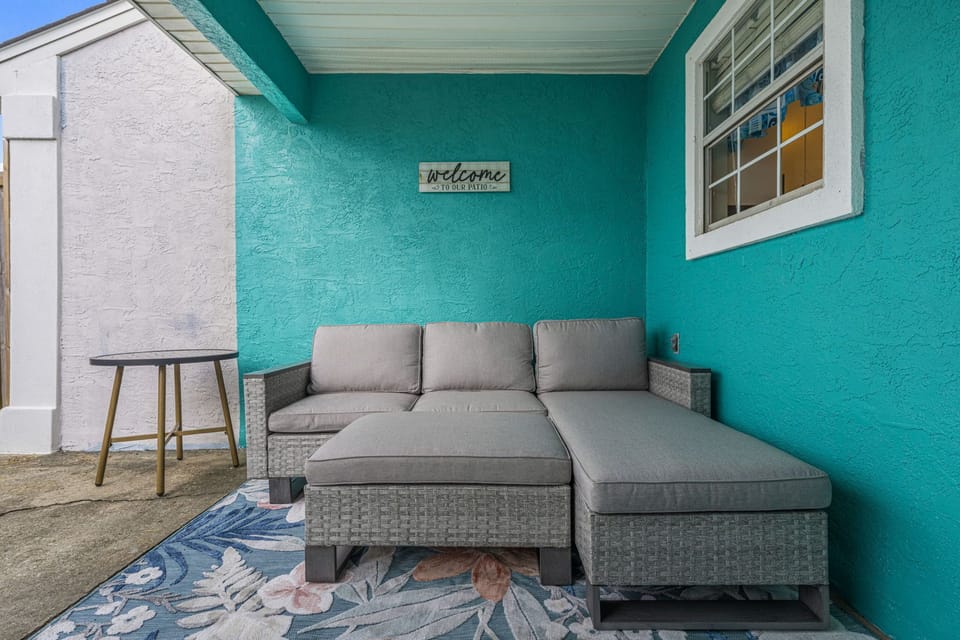 Cozy outdoor seating area with a sectional sofa and vibrant turquoise walls.