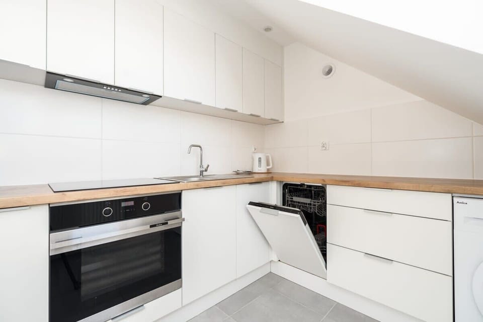 A fully equipped kitchen with white cabinets and wooden countertops, designed to maximize functionality in a compact area.

