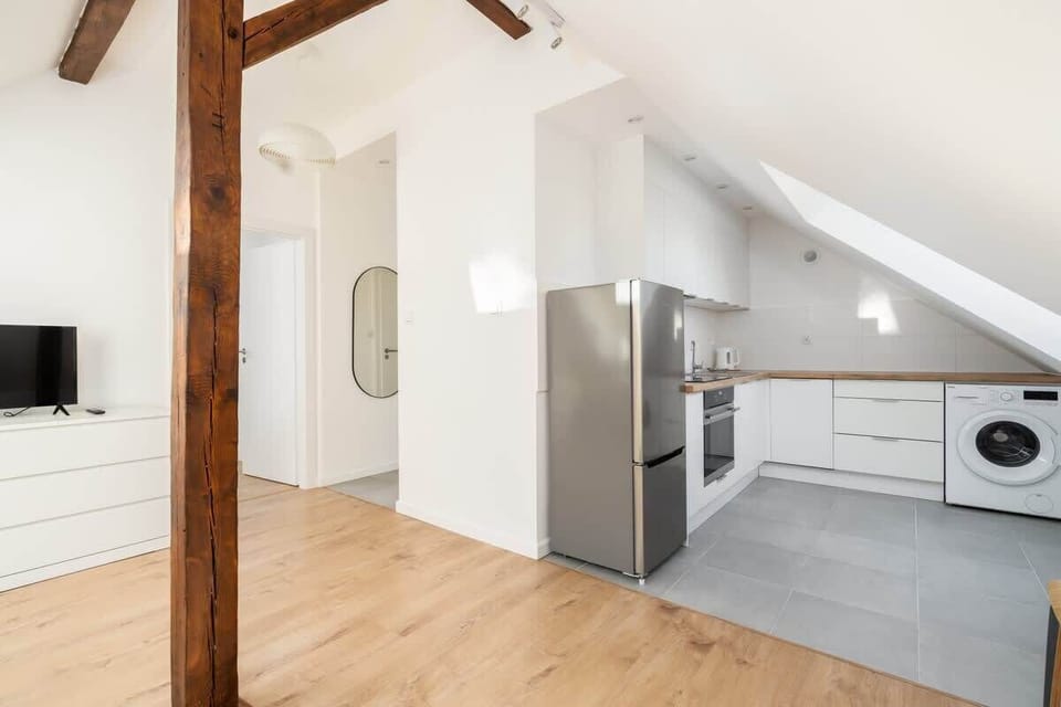 A spacious view of the open-plan attic layout, featuring the kitchen, living, and dining areas harmoniously integrated.

