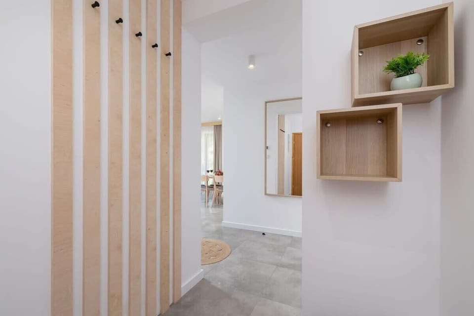 A hallway featuring wooden accents, built-in shelving, and a mirror, combining modern functionality with style.
