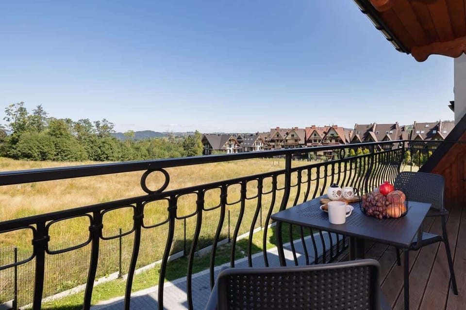 A balcony view overlooking a picturesque landscape, with a table set for two, ideal for enjoying the scenery.
