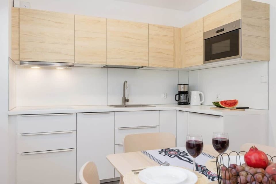 A modern kitchen with wooden upper cabinets, sleek white lower cabinets, and built-in appliances, designed for convenience.
