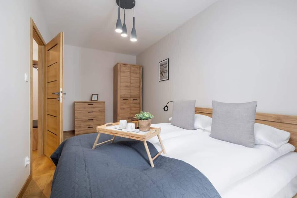 A cozy bedroom with a double bed, gray and white bedding, and wooden furniture, creating a warm and inviting atmosphere.
