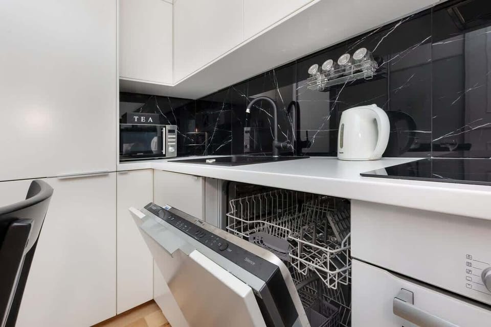 A sleek kitchen layout with high-gloss cabinets, a black backsplash, and built-in appliances, maximizing efficiency and style.
