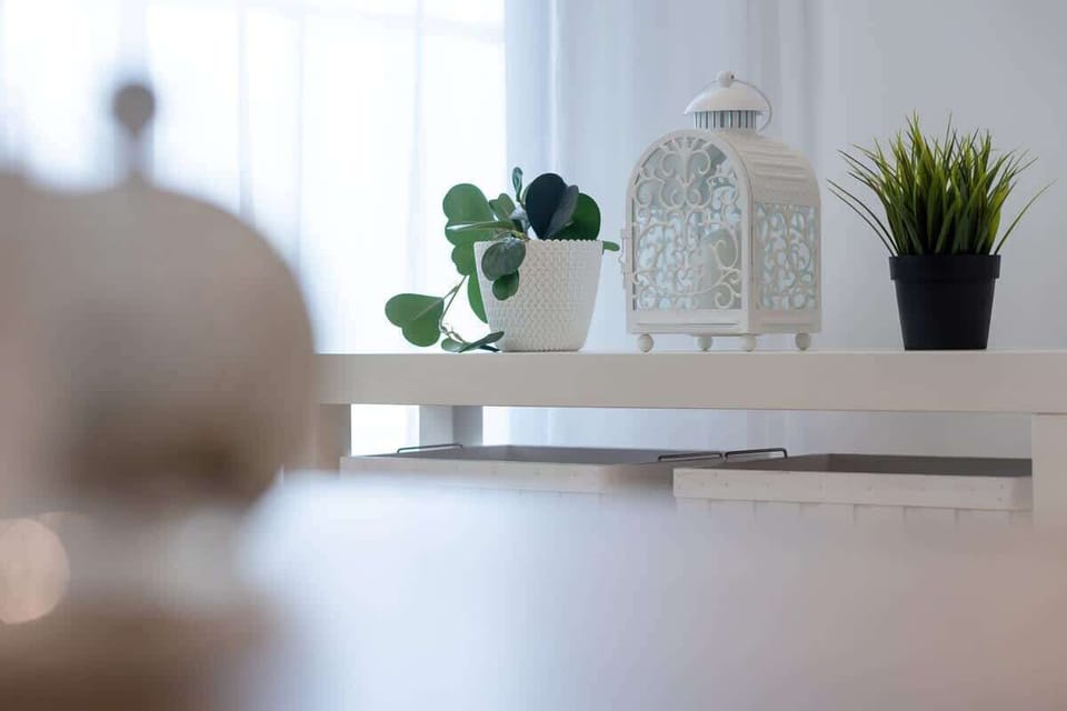 A close-up of a decorative tray on a wooden table, featuring a ceramic vase, a glass lantern, and a potted plant, adding charm and style.
