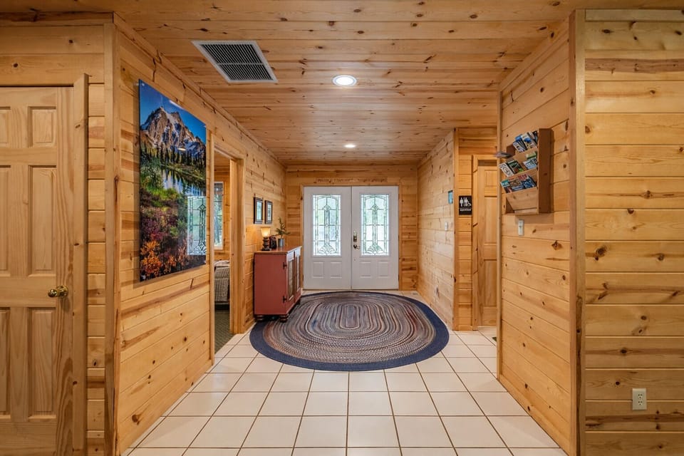 Step into your cozy mountain retreat through this inviting entrance, where rustic charm meets comfort beneath soaring wood ceilings.