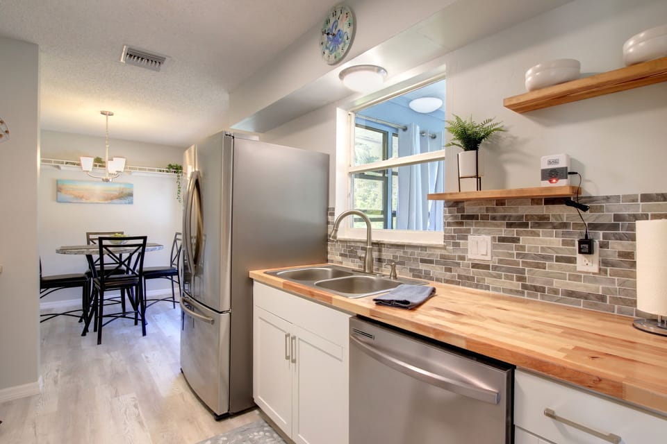View of dishwasher & sink with window access to the game room.